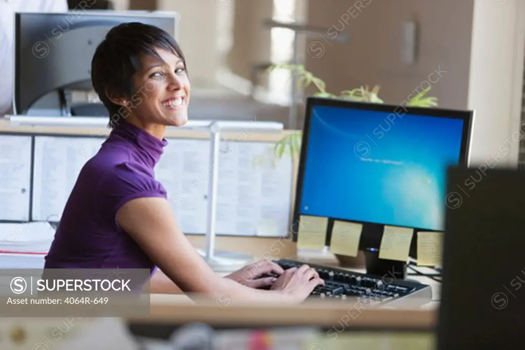 Portrait of businesswoman using computer at office desk