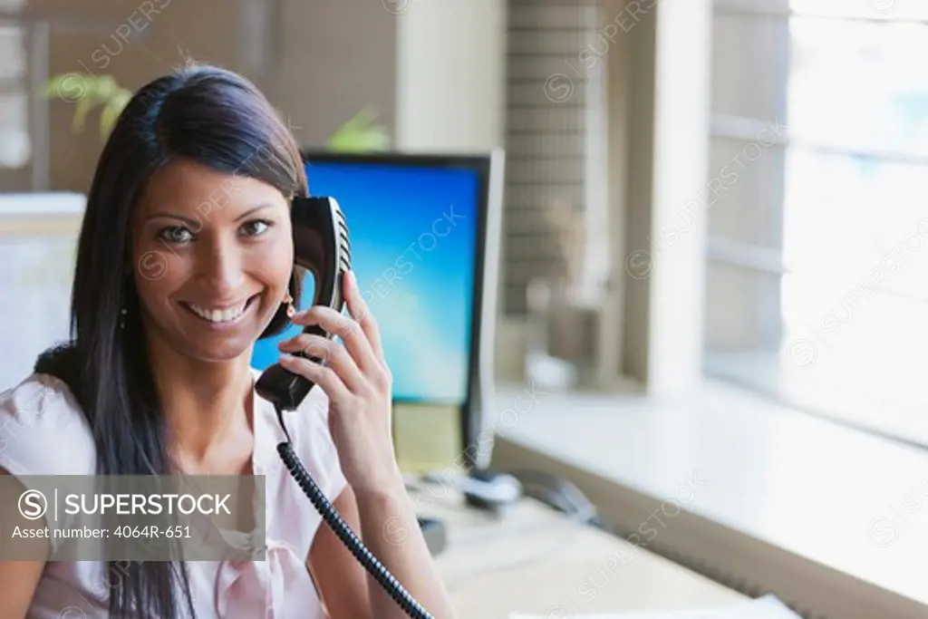 Portrait of businesswoman using telephone in office