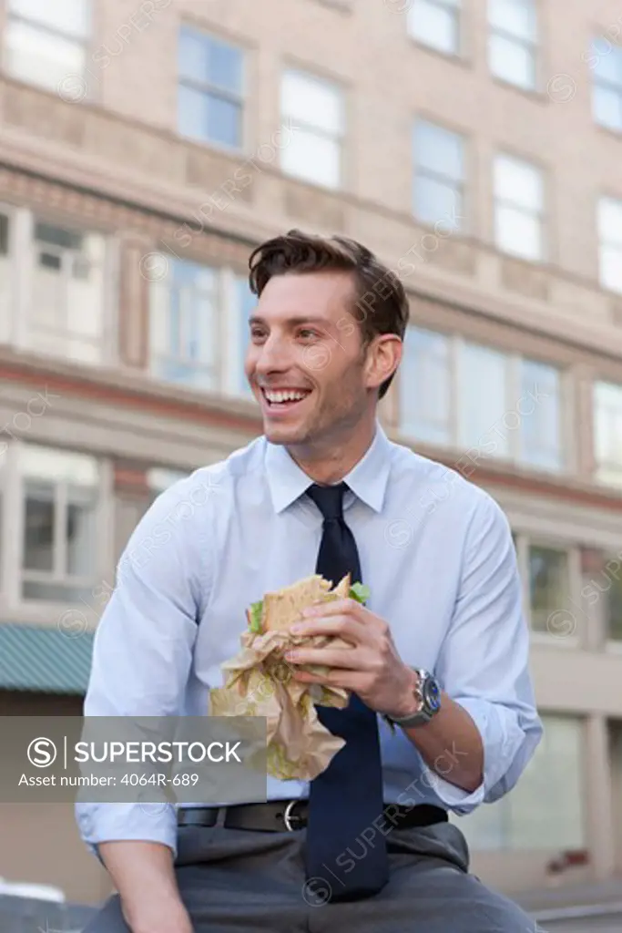 Outdoor portrait of businessman eating sandwich