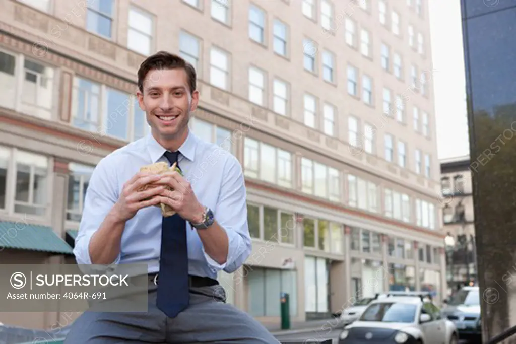 Businessman eating sandwich outside office building