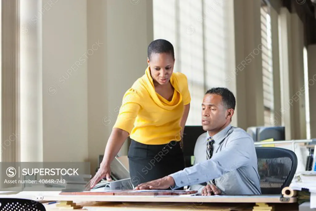 Man and woman consulting at desk in office