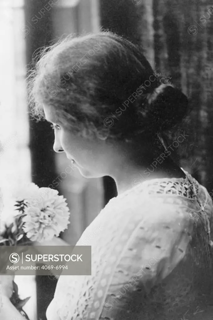 Helen KELLER 1880-1968, American author and lecturer who was blind and deaf from infancy, head and shoulders portrait holding flowers, c. 1912