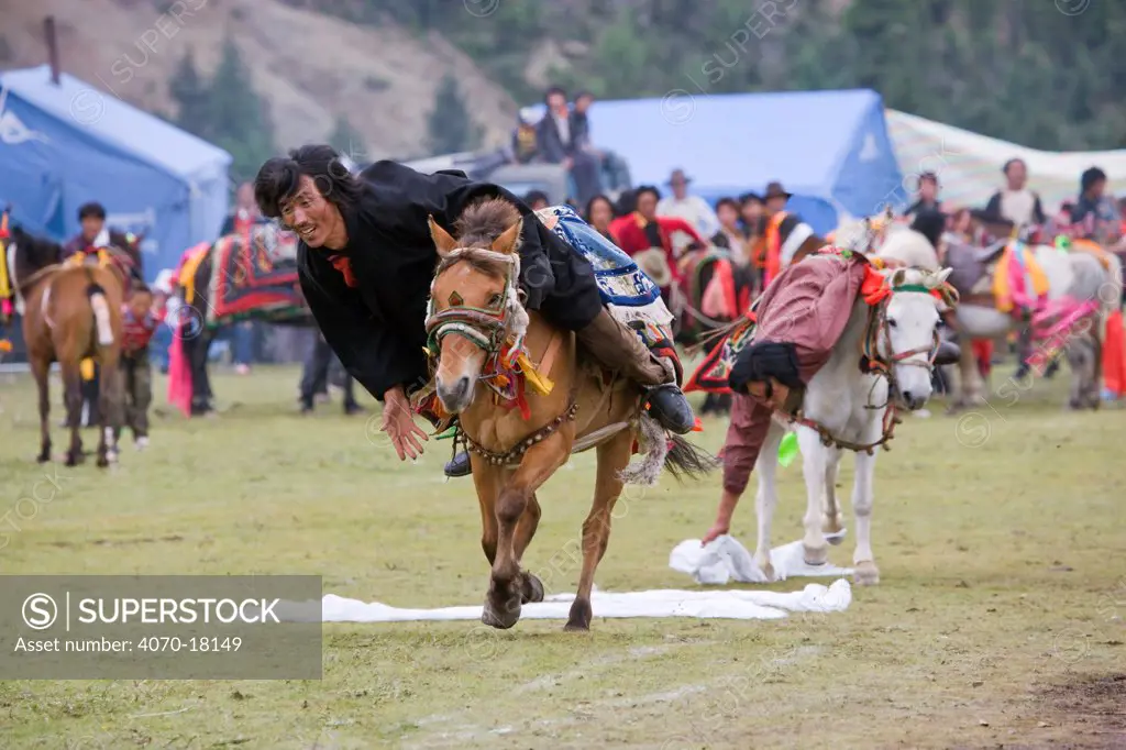 Two Khampa warriors, mounted on their running Tibetan horse, try to catch white scarves, during the horse festival, near Huangyan, in the Garze Tibetan Autonomous Prefecture in the Sichuan Province, China, June 2010