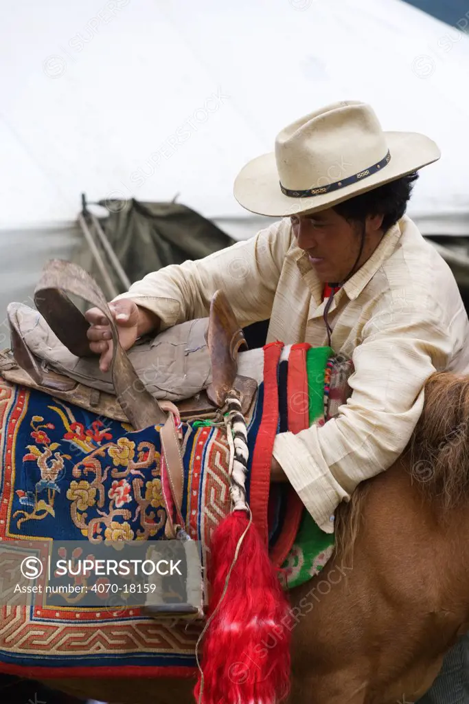 A Khampa warrior saddles his Tibetan horse, during the horse festival, near Huangyan, in the Garze Tibetan Autonomous Prefecture in the Sichuan Province, China, June 2010