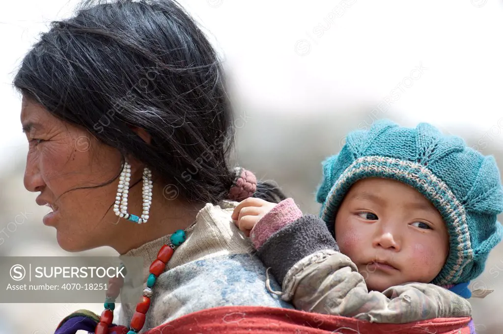 Portrait of Ladakhi woman carrying infant on her back, Phyang, Kardung village, Ladakh, India, June 2010