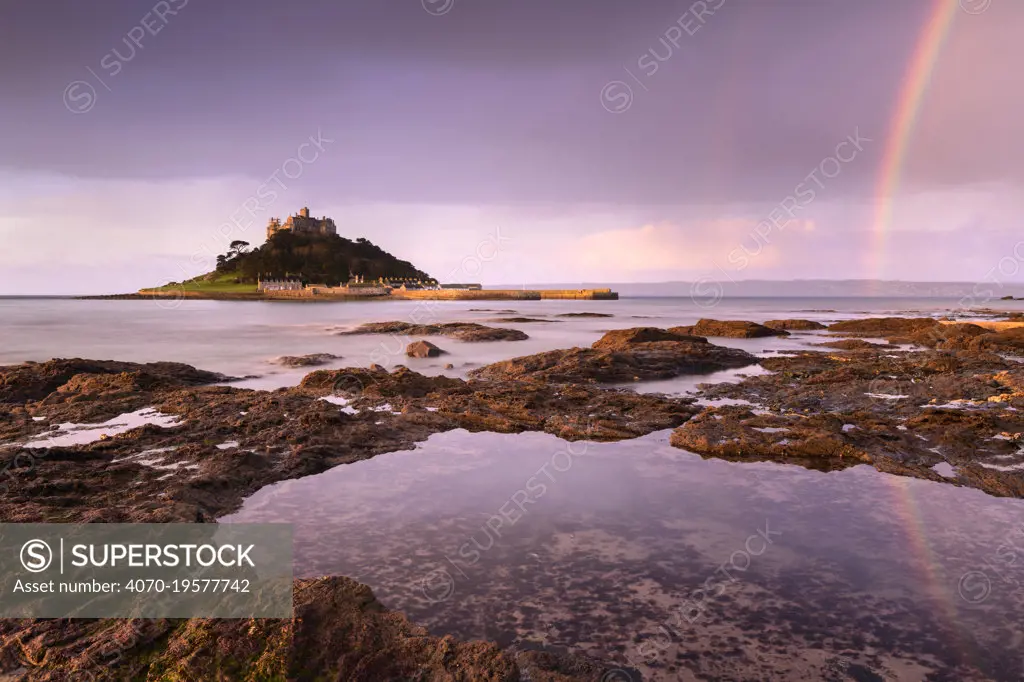 St Michael's Mount at sunrise with a rainbow over Penzance, viewed from Marazion, West Cornwall, UK. February 2019.