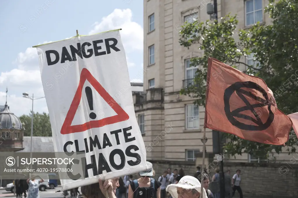 'Danger climate chaos' placard and Extinction Rebellion flag. Climate change protest march, Bristol, England, UK. 16 July 2019.