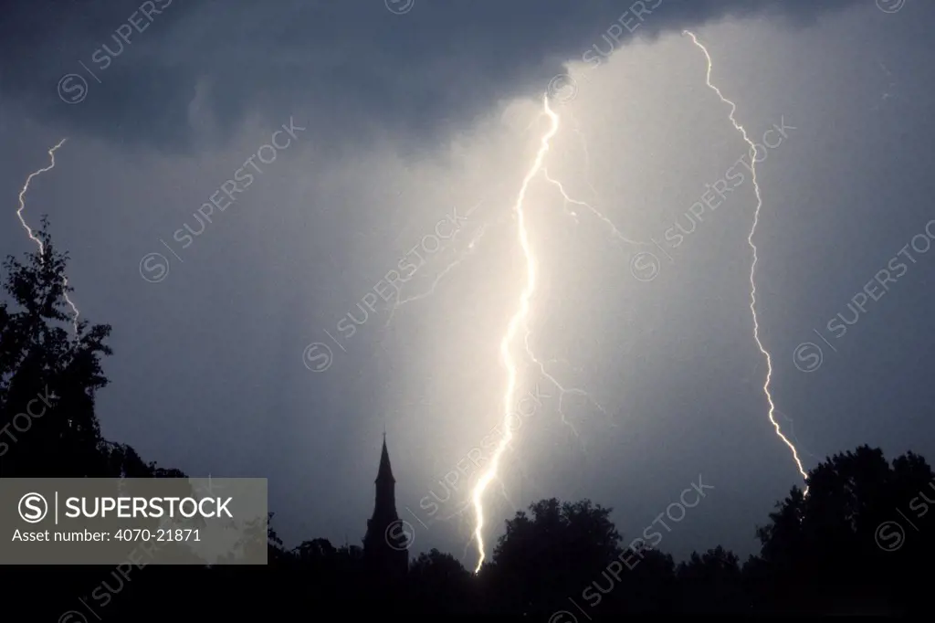 Lightning at night over church tower and trees Belgium