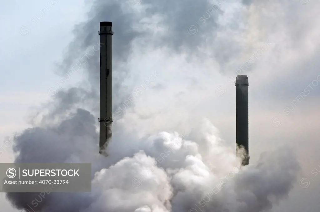 Pollution from petrochemical industry showing chimneys encompassed with smoke, Antwerp harbour, Belgium