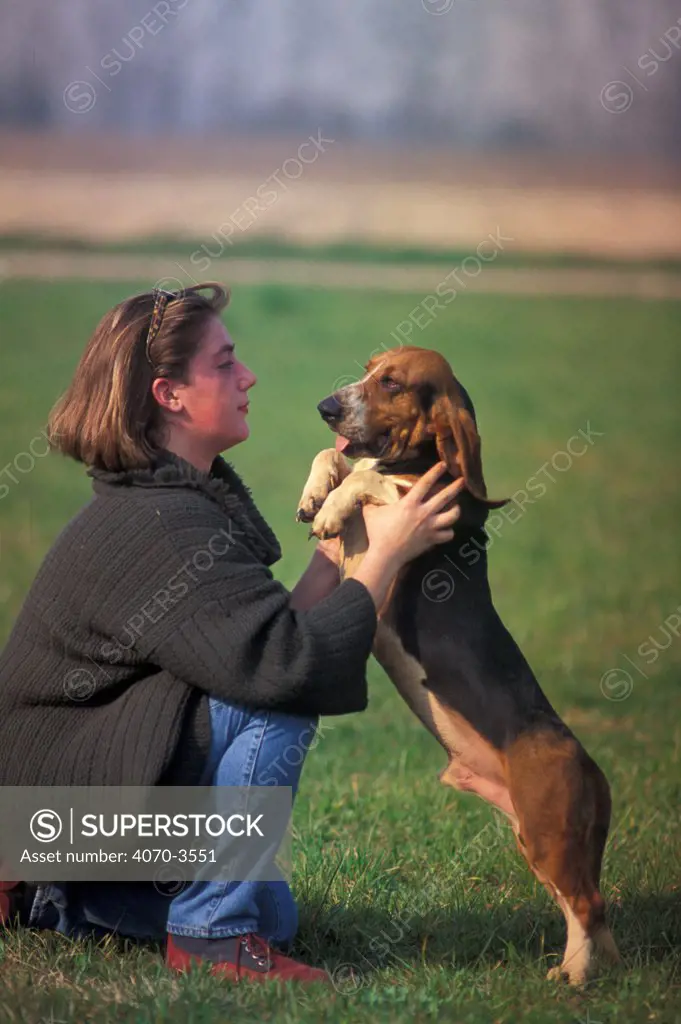 Woman playing with tricolour Artesian Basset Hound.