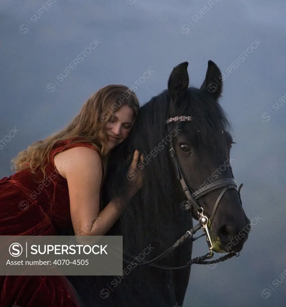 Woman hugging Black friesian stallion Equus caballus}  Ojai, California, USA. 