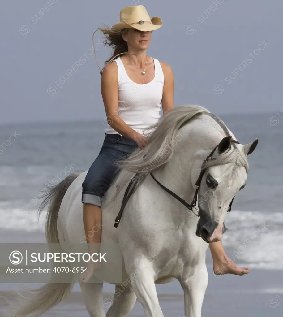 Woman riding grey Arabian stallion bareback on the beach, Ojai, California, USA, model released