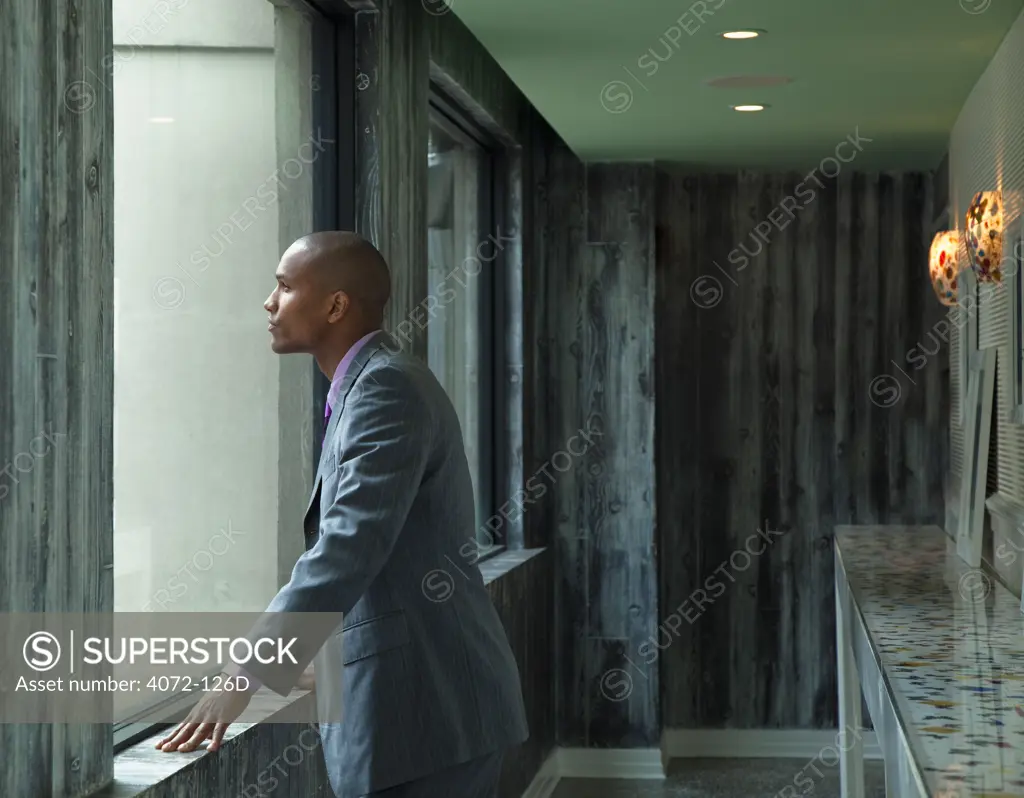 Businessman looking out through the window of a hotel corridor