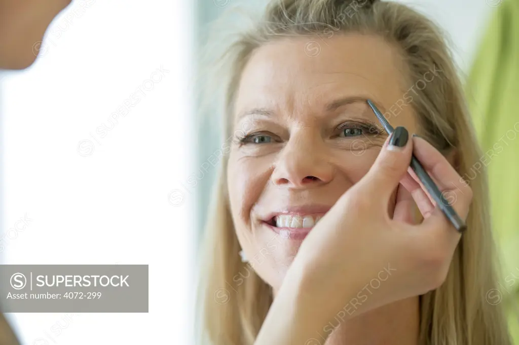 Mature woman having her make-up applied