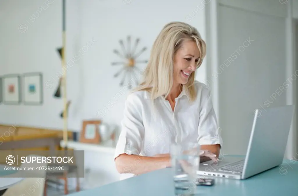 Businesswoman smiling while using a laptop at home