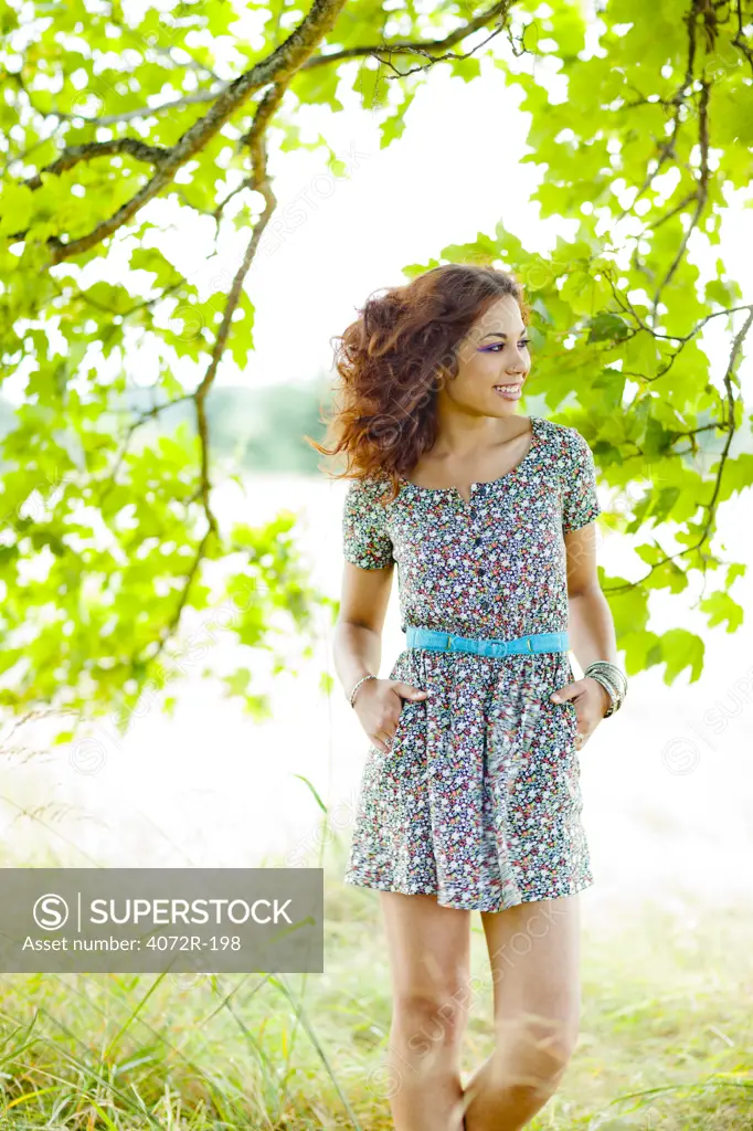 Happy, smiling woman standing under tree