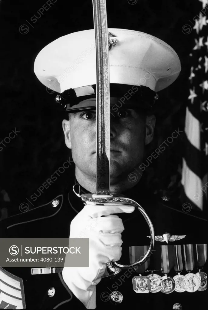 Marine officer holding a sword in front of his face