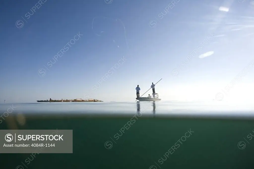 Over and Underwater View of Two Men Fly Fishing in Boat Near Shipwreck, Florida Keys, USA
