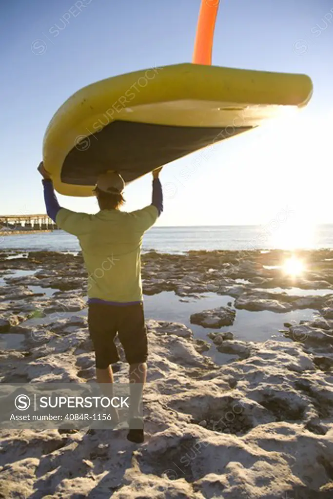 Man Carrying Paddleboard on Beach, Florida Keys, USA
