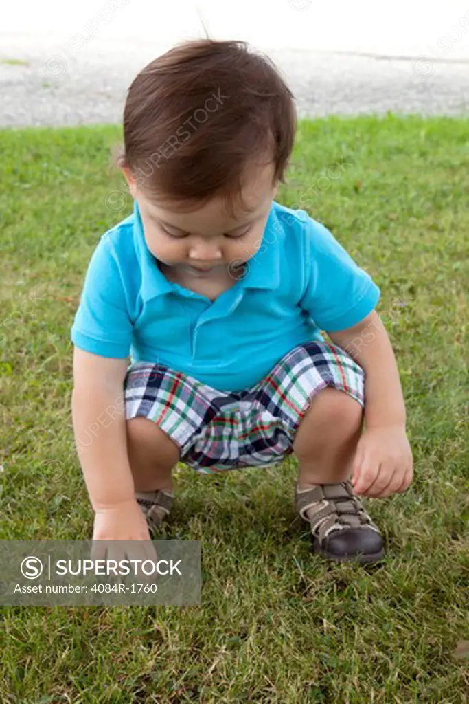 Young Boy Squatting in Grass