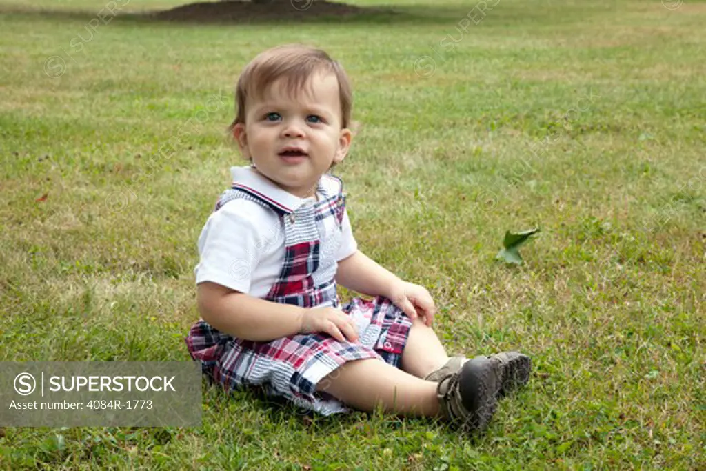 Young Boy Sitting in Grass, Portrait