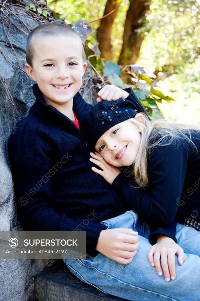 Smiling Boy and Girl Sitting on Stone Ledge, Portrait