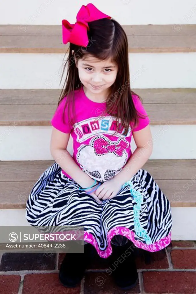 Young Girl in Animal Print Skirt and Pink Bow in Hair Sitting on Porch Steps, Portrait