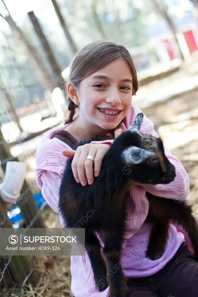 Girl holding a kid goat in a petting zoo