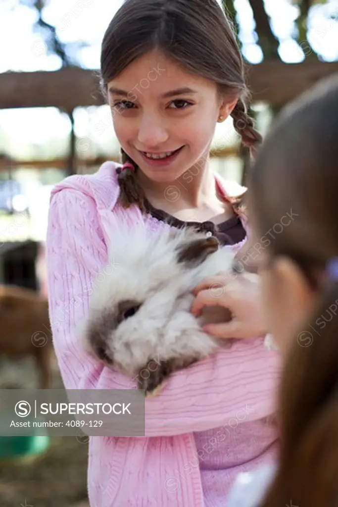 Girl holding a rabbit in a petting zoo
