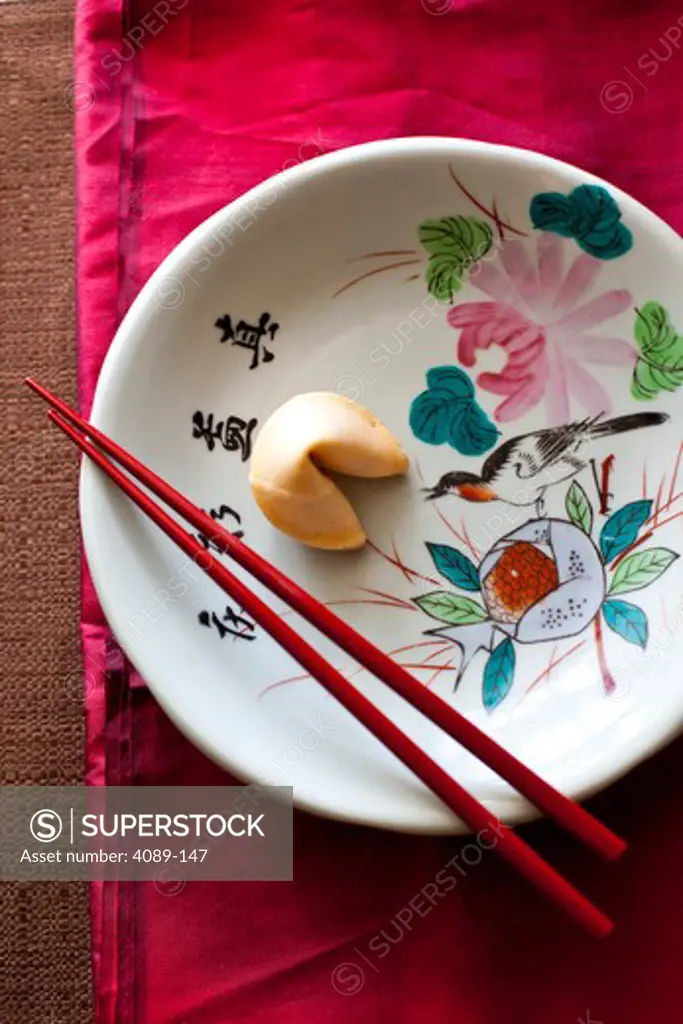 Chopsticks and a fortune cookie in a decorative Asian plate