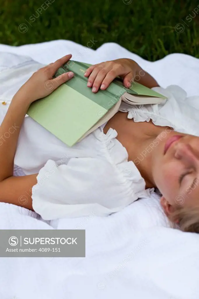 Young woman sleeping with a book in lawn