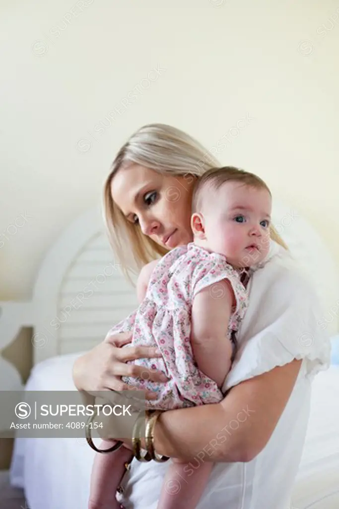Young woman holding her daughter in bedroom