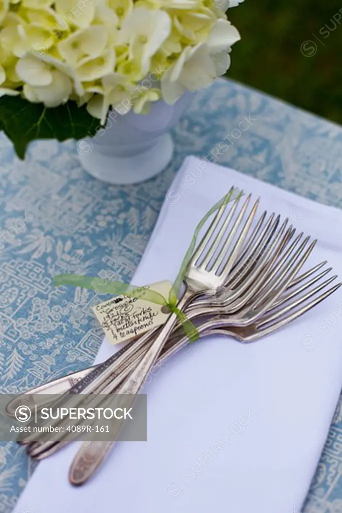 Antique forks with a vase of Hydrangeas on a dining table