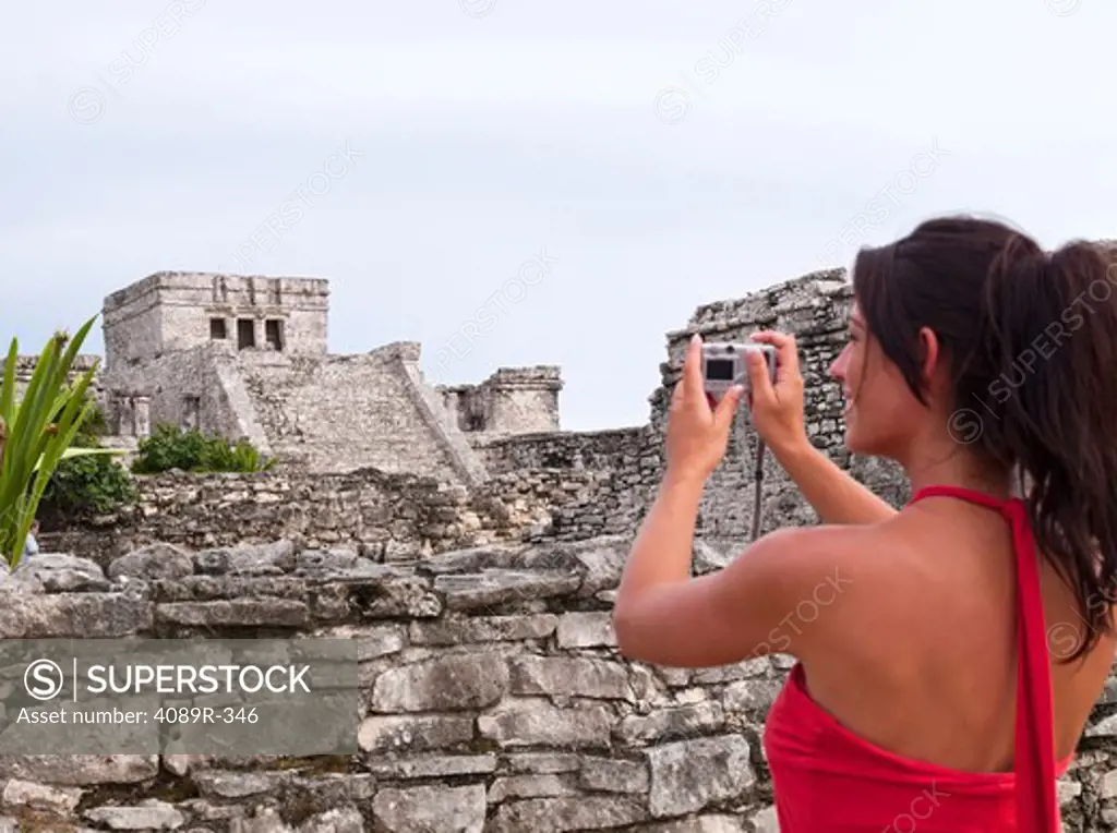 Mexico, Quintana Roo, Tulum, Young woman photographing pyramid at archaeological site