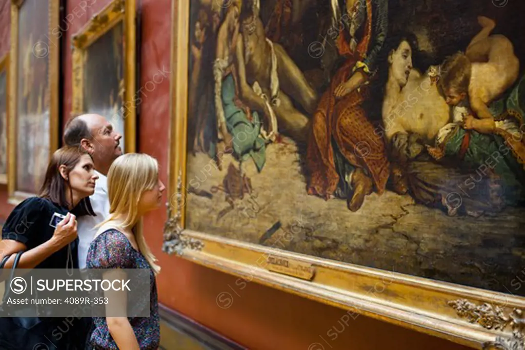 Teenage girl with her parents looking at a painting in a museum, Paris, Ile-de-France, France