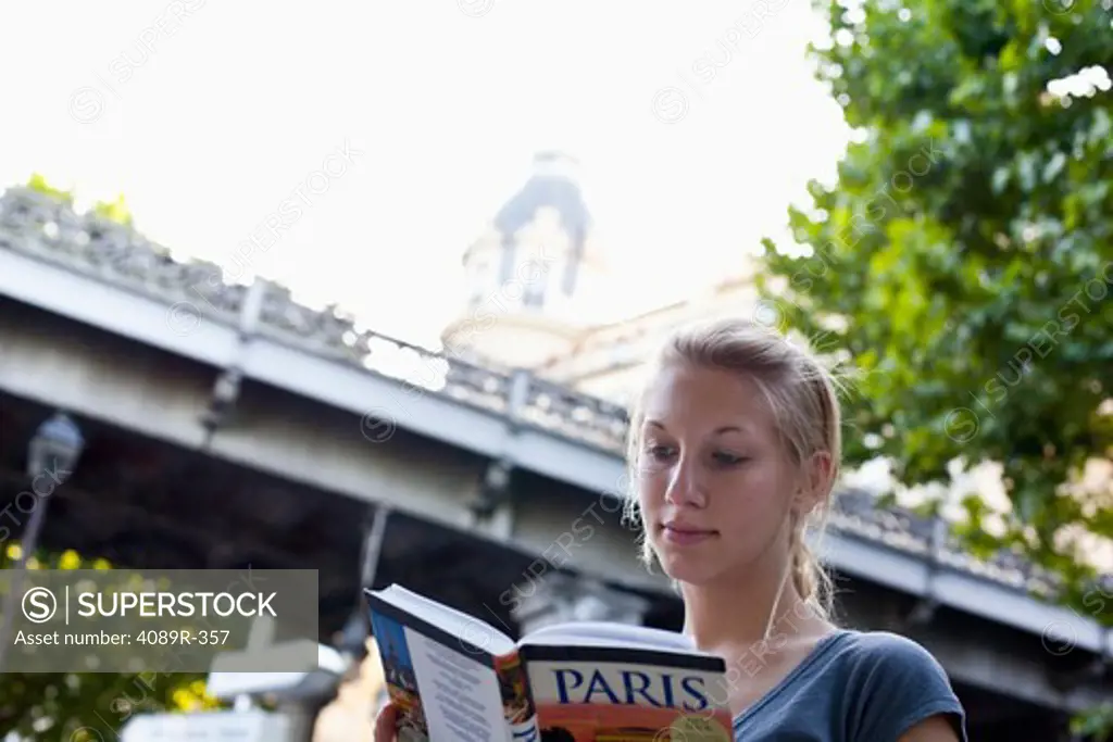 Teenage girl reading a guidebook, Paris, Ile-de-France, France