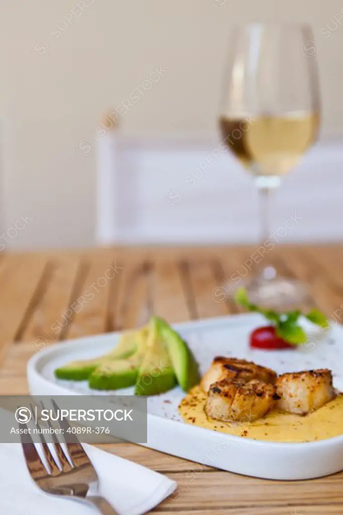 Close up of scallop appetizer with avocados and white wine