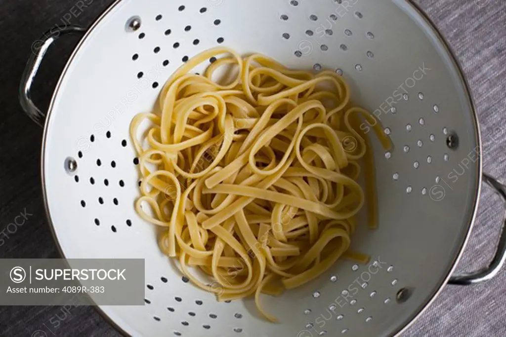Overhead view of cooked linguini in colander