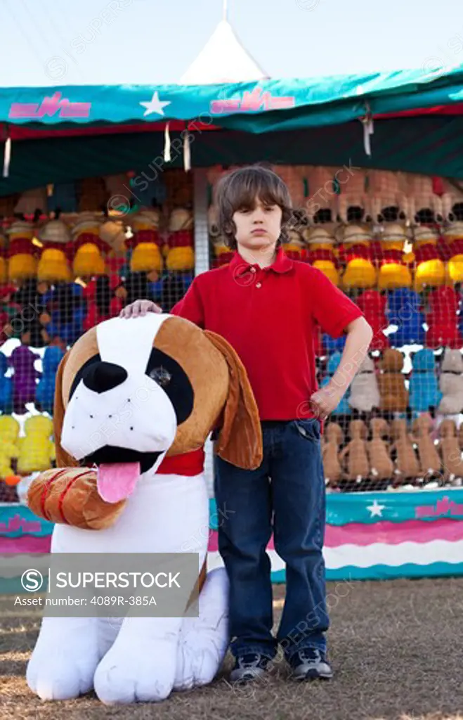 Boy posing with toy dog winning at fair, front view