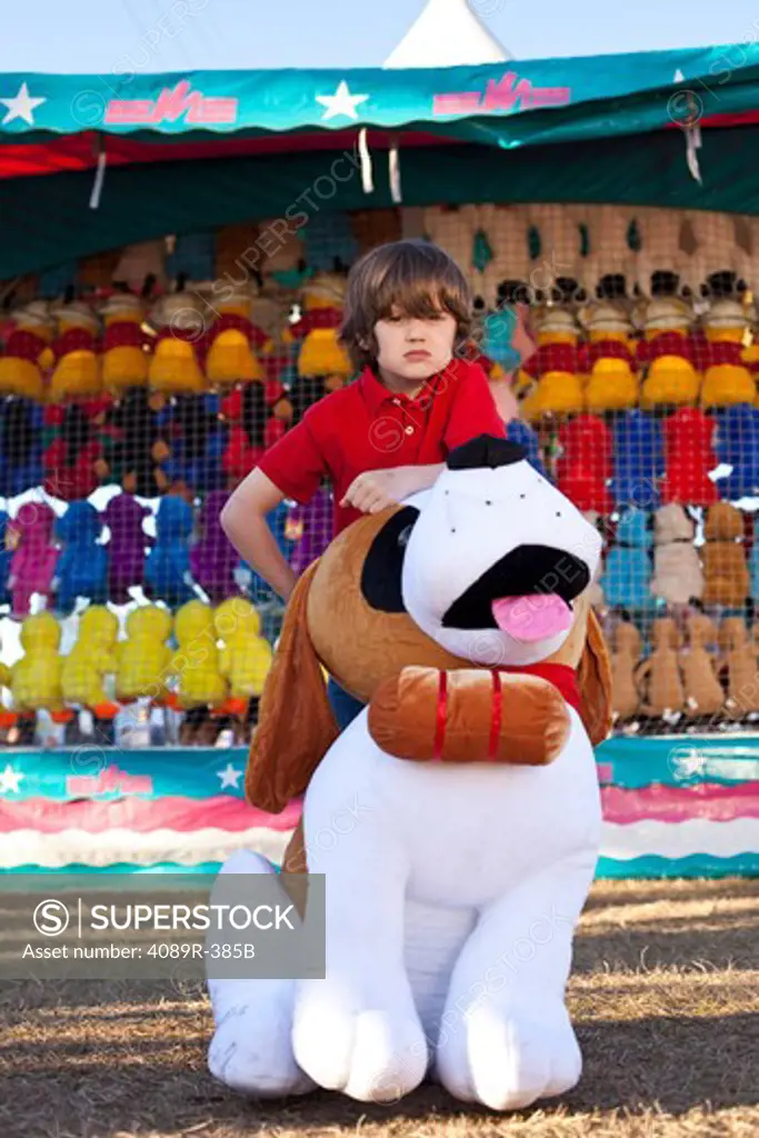 Boy posing with toy dog winning at fair, front view