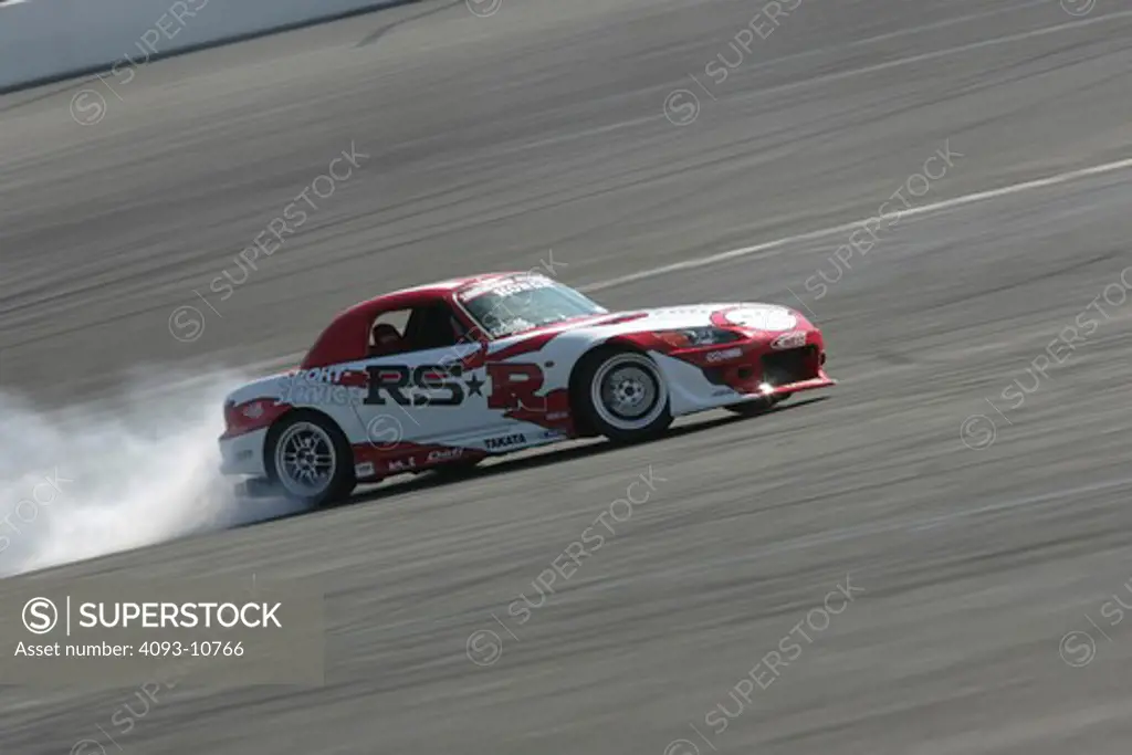 2004 Honda s2000 s-2000 Hardtop racing version race type burning rubber on the race track white smoke    S2000 features a front-mid-engine, rear wheel drive layout with power being delivered via a Torsen limited slip differential mated to a six-speed manual transmission.  The S2000 comes with an electrically powered cloth top, and an OEM hardtop is also available.  The 2004 model introduced newly designed 17 wheels and Bridgestone RE-050 tires along with a retuned suspension that reduced the car