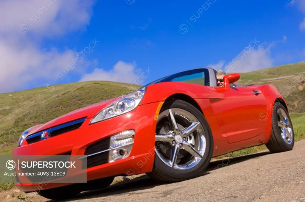 2007 Saturn Sky on an empty road in the hills grassy hills foothills