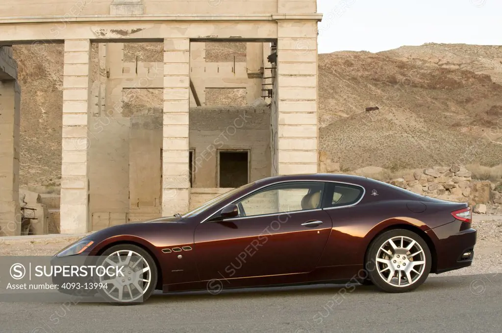Maserati GranTurismo parked by old building, side view