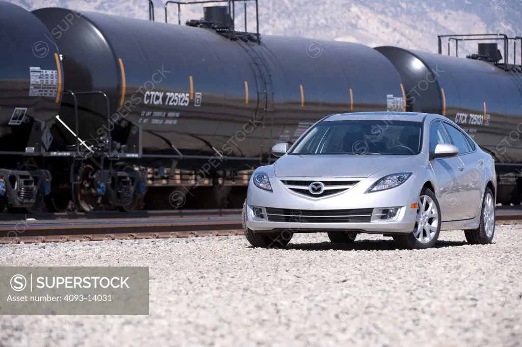 Silver Mazda 6 parked by goods train, front view