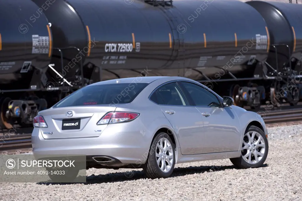 Silver Mazda 6 parked by goods train, rear view