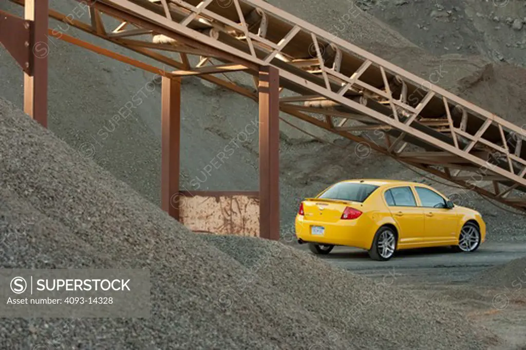 Yellow Chevrolet Cobalt SS parked amid machinery in quarry