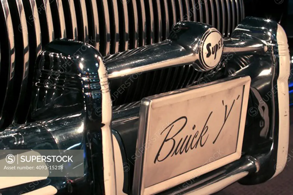 1938 Buick Y Y Job Y-Job black in a showroom. close up of the grill and the license plate The 1938 Buick Y-Job is claimed to be the first concept car in history Designed by Harley J. Earl, the car had power-operated hidden headlamps, gunsight hood ornament, wraparound bumpers, flush door handles, and prefigured styling cues used by Buick until the 1950s.