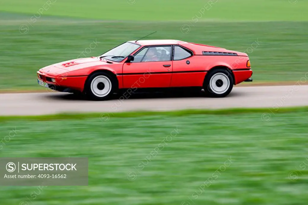 Action shot of a red 1978 BMW M1 on a rural road in Germany. The BMW M1 is a supercar produced by the German automaker BMW from 1978 to 1981. It was the first and only mid-engined BMW. It employed a twin-cam M88/1 3.5 L 6-cylinder gasoline engine. The M1 coupe was hand-built between 1978 and 1981 under the Motorsport division of BMW as a homologation special for sports car racing. The body was designed by Giugiaro.
