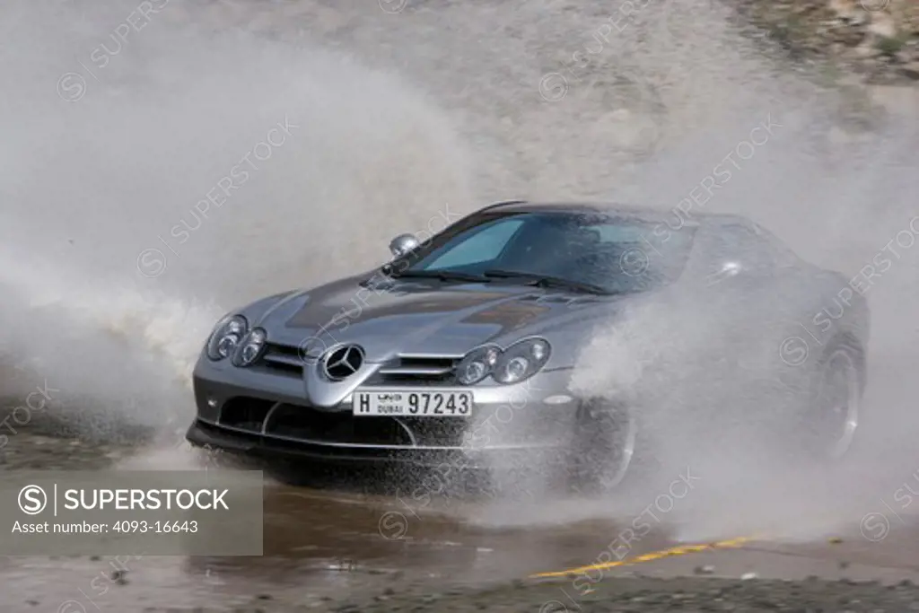 An action shot of a 2007 Mercedes-Benz McLaren SLR 722 going through a low water crossing and throwing a spray of water into the air. The 722 refers to the victory by Stirling Moss and his co-driver Denis Jenkinson in a Mercedes-Benz 300 SLR with the starting number 722 (indicating a start time of 7:22 a.m.) at the Mille Miglia in 1955. The 722 Edition creates 650 bhp, with a top speed of 337 km/h (5 more than the standard SLR). A new suspension is used with 19-inch light-alloy wheels, a stiffer