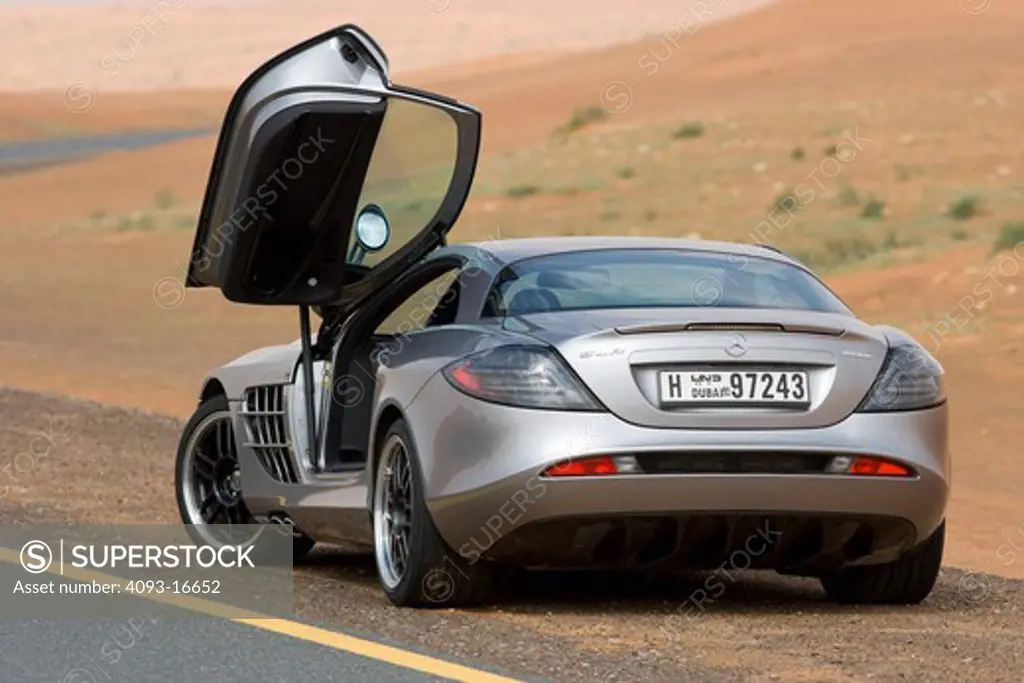 A rear 3/4 view of a 2007 Mercedes-Benz McLaren SLR 722 with the drivers-side gullwing door open. The 722 refers to the victory by Stirling Moss and his co-driver Denis Jenkinson in a Mercedes-Benz 300 SLR with the starting number 722 (indicating a start time of 7:22 a.m.) at the Mille Miglia in 1955. The 722 Edition creates 650 bhp, with a top speed of 337 km/h (5 more than the standard SLR). A new suspension is used with 19-inch light-alloy wheels, a stiffer damper configuration and 0.4 inches
